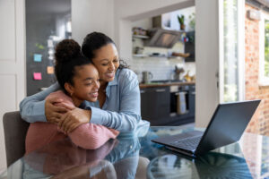 Mother and daughter getting good news online and celebrating by hugging